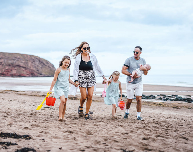 Family walking along the beach at Pease Bay with buckets and spades 