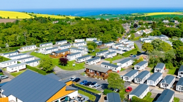 Drone image of Coldingham Bay Leisure Park with caravans and The Drift Inn bar and restaurant, the horizon of the sea is in the background 