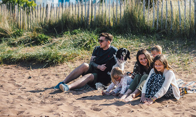 Family with a dog sitting on the beach 
