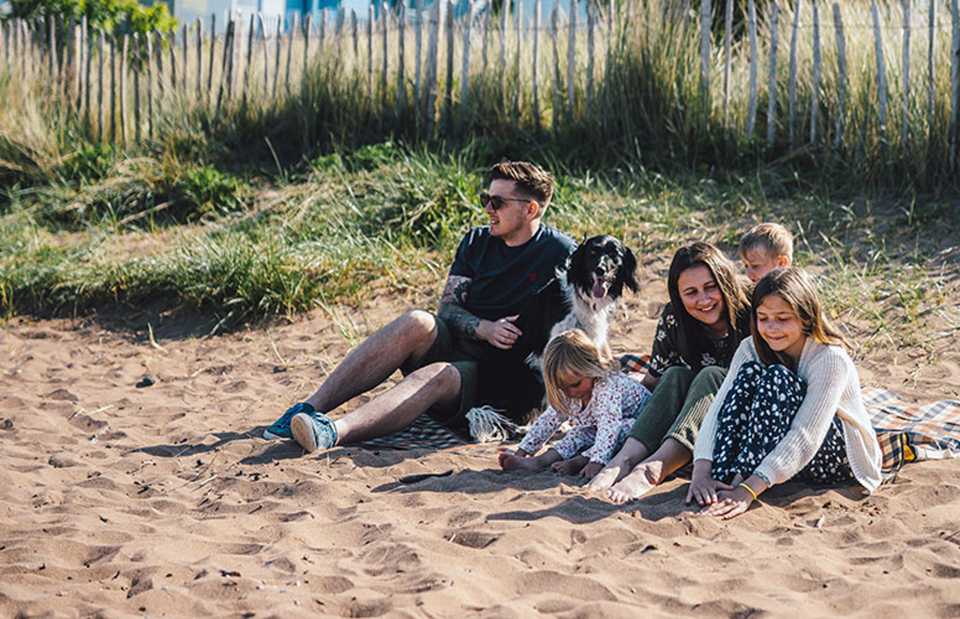 Family with a dog sitting on the beach 
