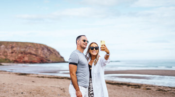 Couple taking a selfie on the beach at Pease Bay