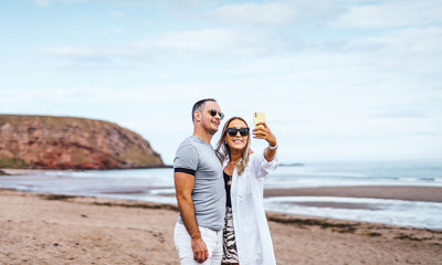 Couple taking a selfie on the beach at Pease Bay