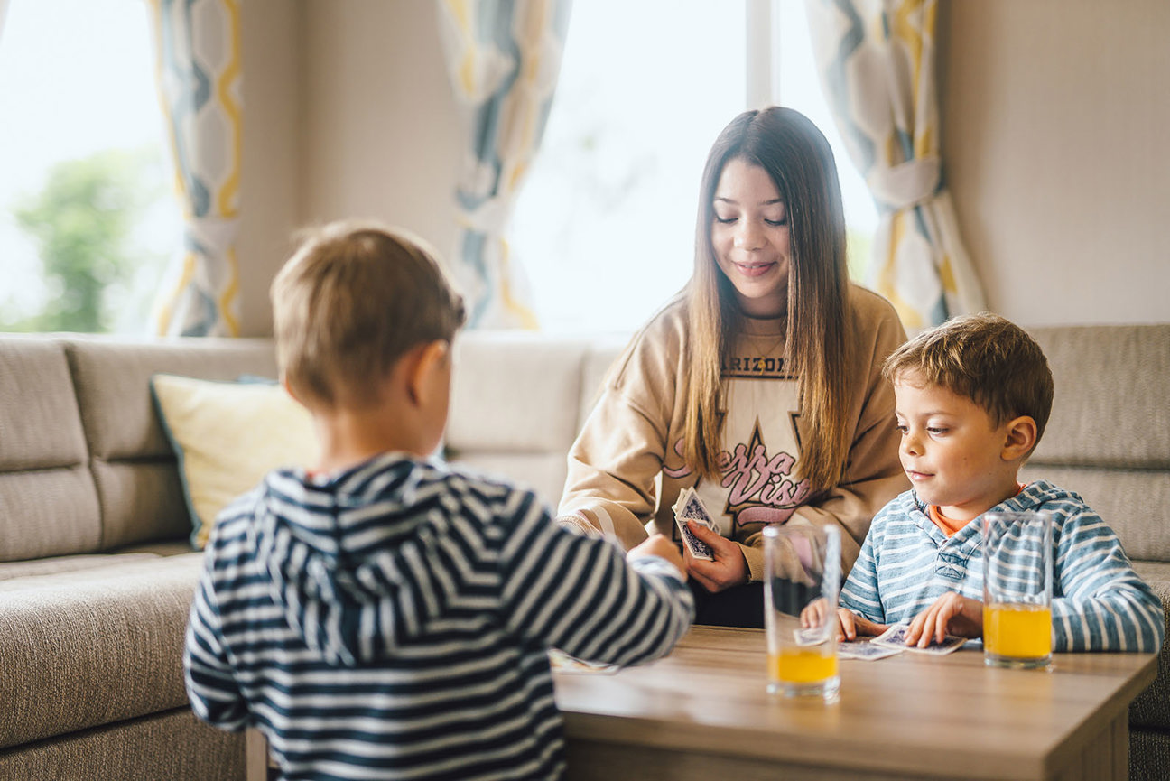 Children playing a card game in caravan accommodation at Coldingham Bay