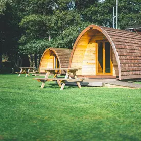 Camping pod accommodation with picnic benches on the grass 