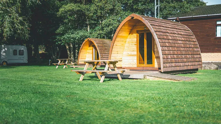 Camping pod accommodation with picnic benches on the grass 