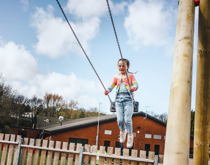 Child on swing at play area at Thurston Manor