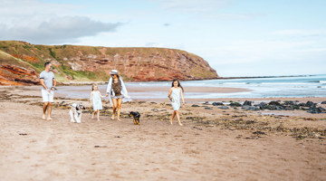 Family with dogs walking on the beach at Pease Bay